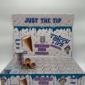 A stylish and colorful box labeled 'Trippy Tips Birthday Cake Blue Meanies Shrooms Cone Master Box,' showcasing pre-rolled cones filled with a blend of Blue Meanies mushrooms and birthday cake flavor. The cones and packaging highlight the product’s convenience, quality, and unique flavor combination