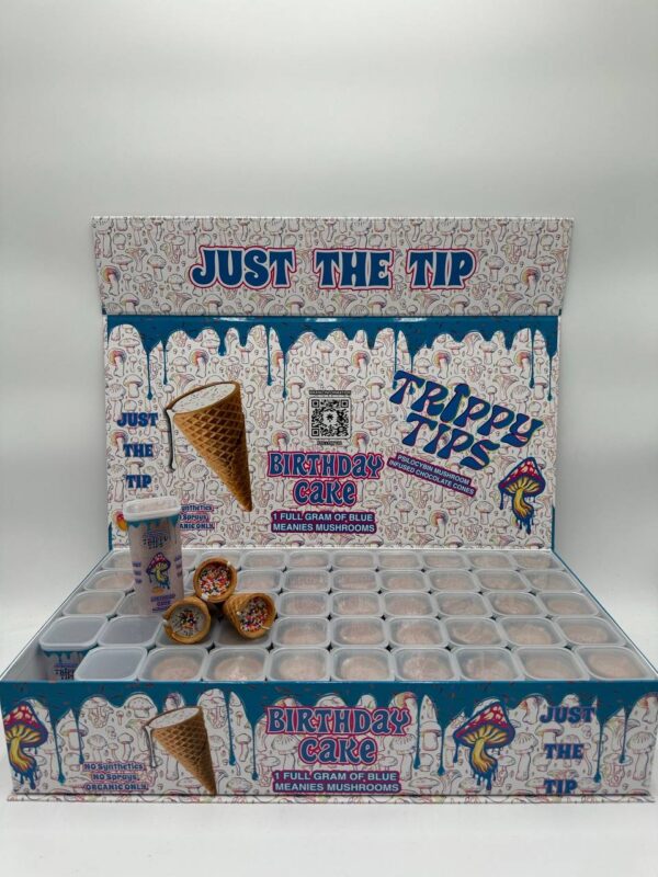 A stylish and colorful box labeled 'Trippy Tips Birthday Cake Blue Meanies Shrooms Cone Master Box,' showcasing pre-rolled cones filled with a blend of Blue Meanies mushrooms and birthday cake flavor. The cones and packaging highlight the product’s convenience, quality, and unique flavor combination